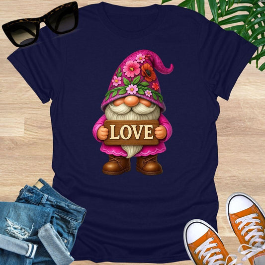 Navy blue t-shirt with a gnome holding a 'LOVE' sign on a wooden surface with sunglasses, jeans, and shoes.