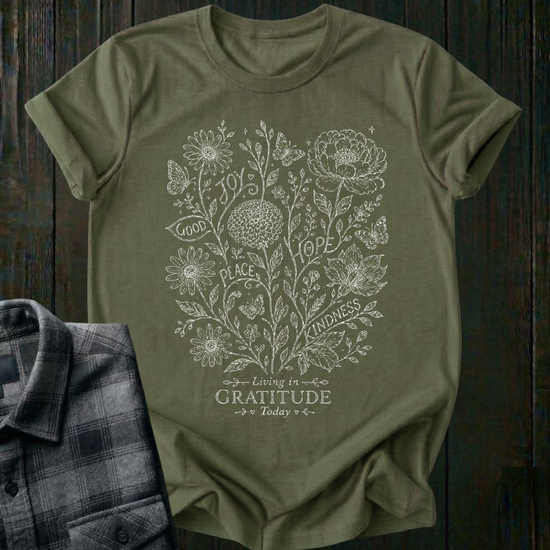 Vintage botanical illustration featuring flowers, butterflies, leaves, and the inspirational words joy, hope, peace, kindness, and good above the phrase Living in Gratitude Today on a military green shirt