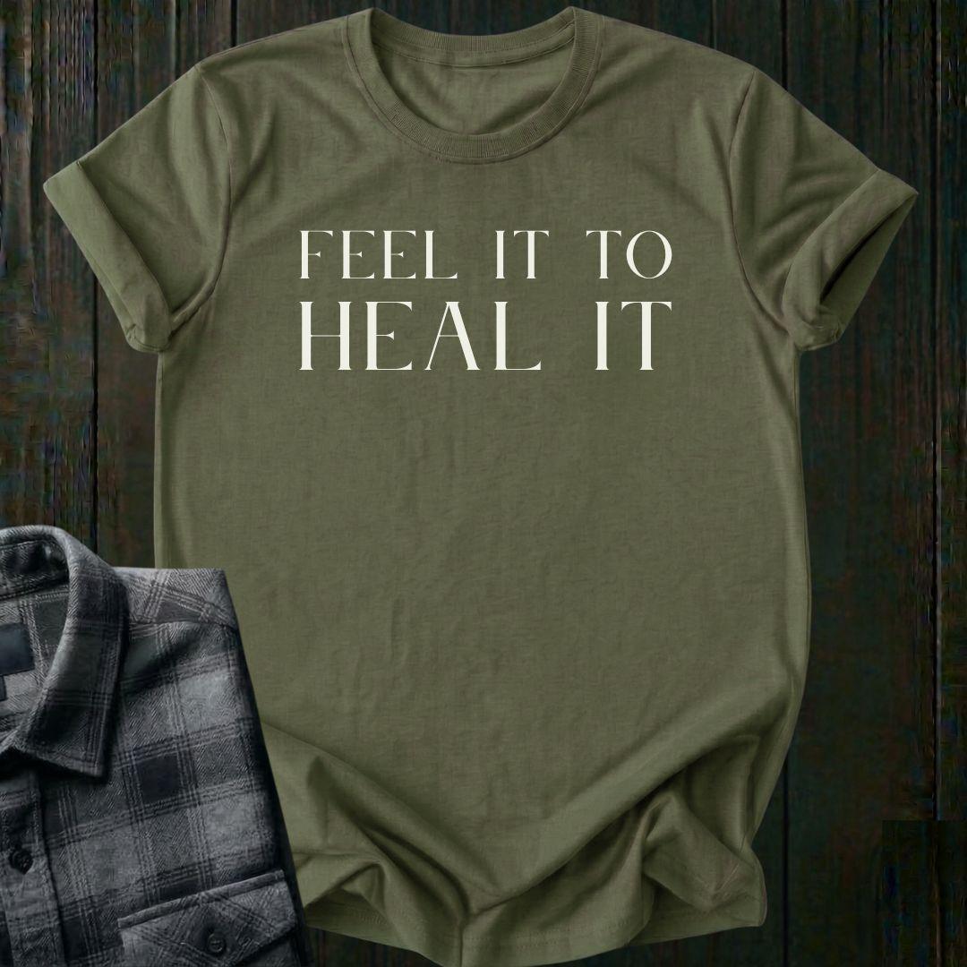 Minimalist typography design featuring the phrase "Feel It to Heal It" in elegant serif lettering on a military green tee.
