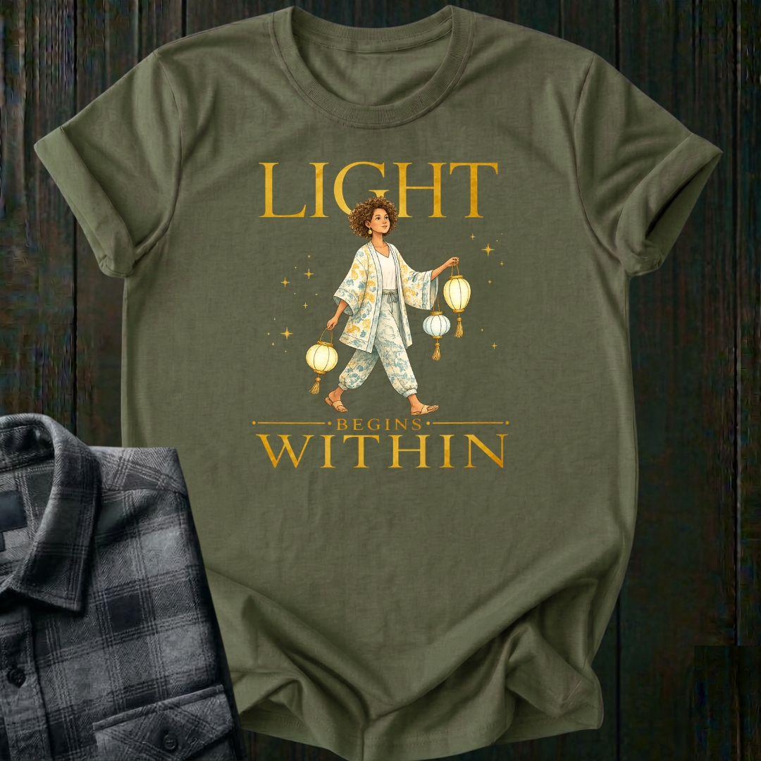 Illustrated woman carrying glowing paper lanterns beneath the words "Light Begins Within," symbolizing inner light, hope, mindfulness, and personal growth on a military green tee