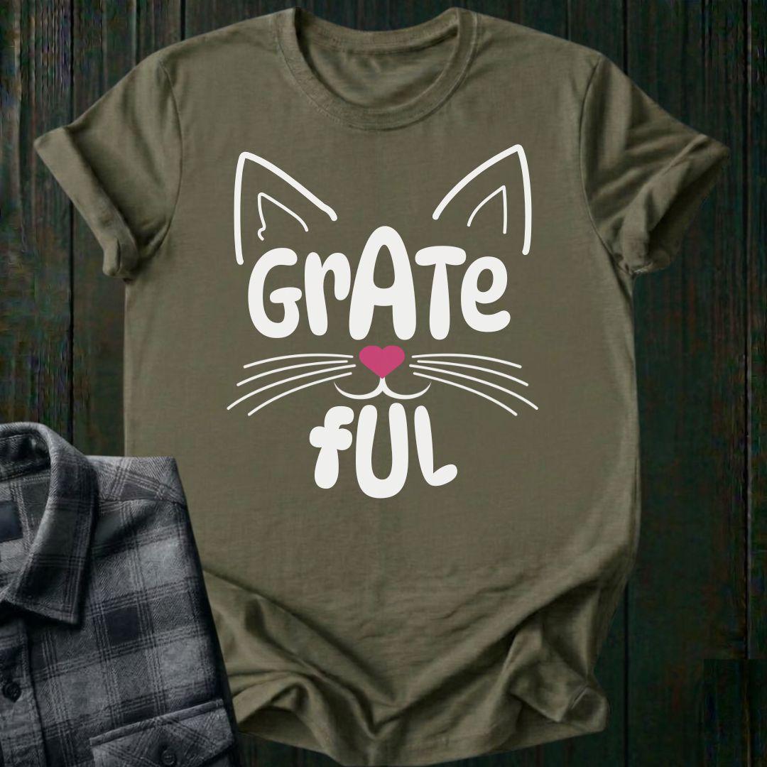 Green t-shirt with cat face design and 'Grate Ful' text on a wooden surface