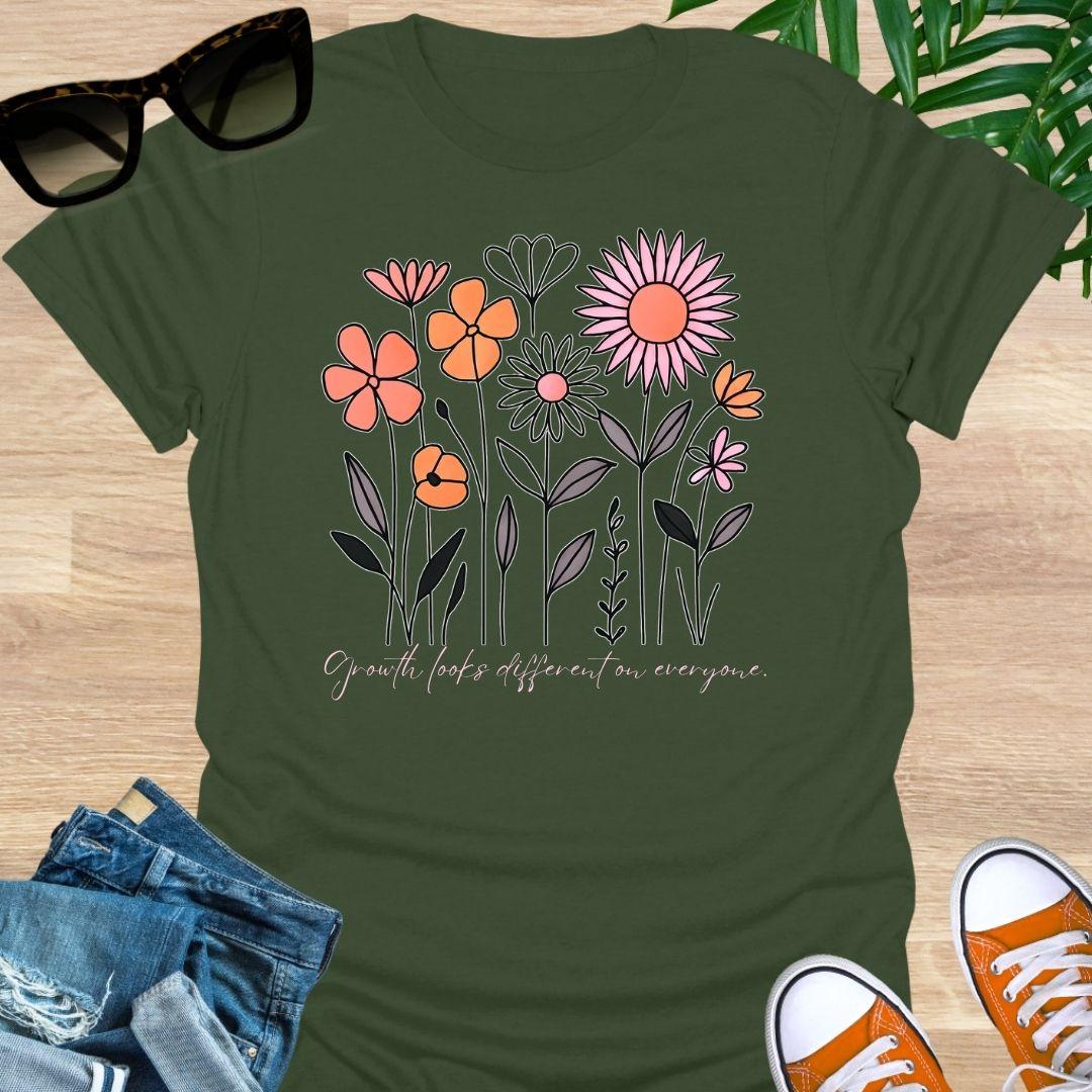 Military Green unisex t-shirt. Hand-drawn wildflowers with the script “Growth looks different on everyone” 