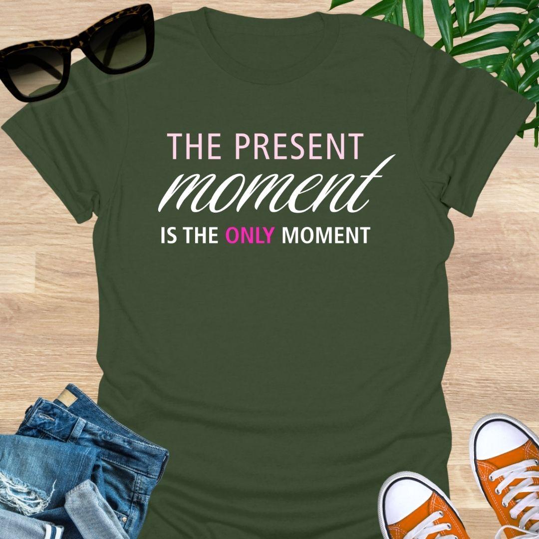 Military Green tee with pink/white text reading “The Present Moment Is the Only Moment” minimalist mindfulness graphic.