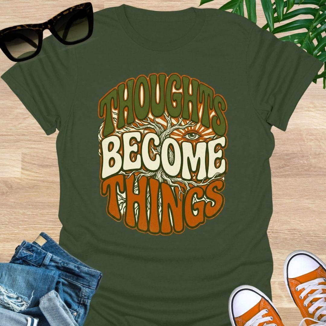 Retro design with tree roots, an eye, and the phrase “Thoughts Become Things” in earthy colors on a military green unisex tee.