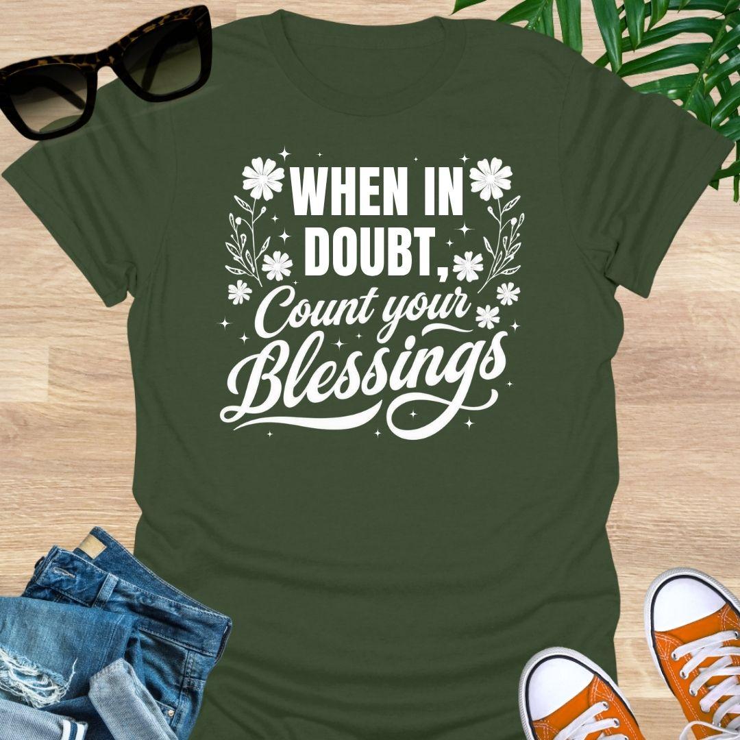 “When in Doubt, Count Your Blessings” in white script with floral and sparkle accents on a military green unisex tee.