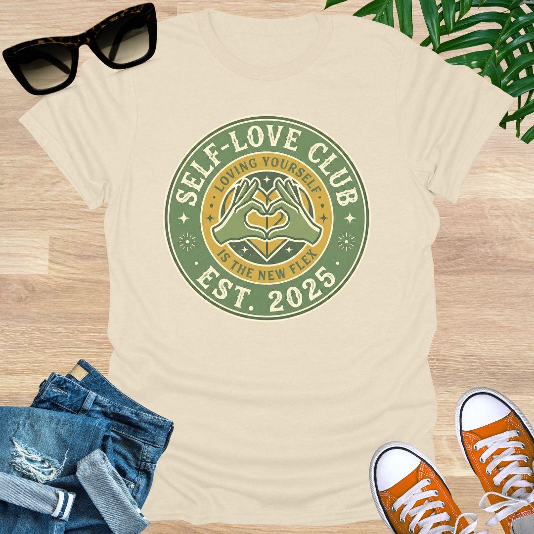 Vintage badge-style design with hands forming a heart and text “Self-Love Club – Loving Yourself Is the New Flex.” on a natural unisex tee