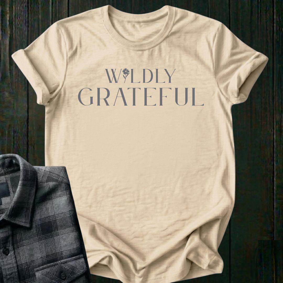 Elegant typography design featuring the phrase "Wildly Grateful" with a flower replacing the letter I in Wildly on a beige tee