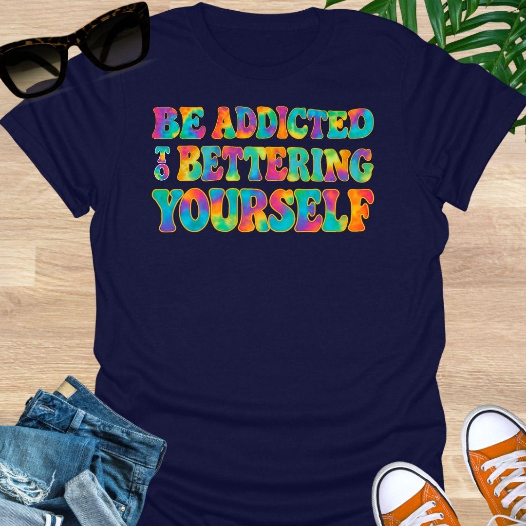 Rainbow tie-dye “Be Addicted to Bettering Yourself” text on navy unisex growth-mindset tee.