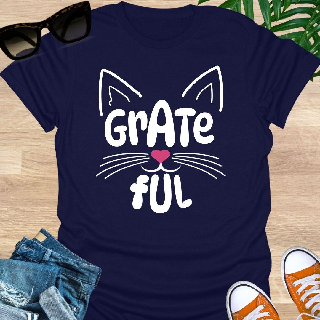 Navy blue unisex graphic t-shirt with cat ears, whiskers, and a pink heart nose forming the word GRATEFUL