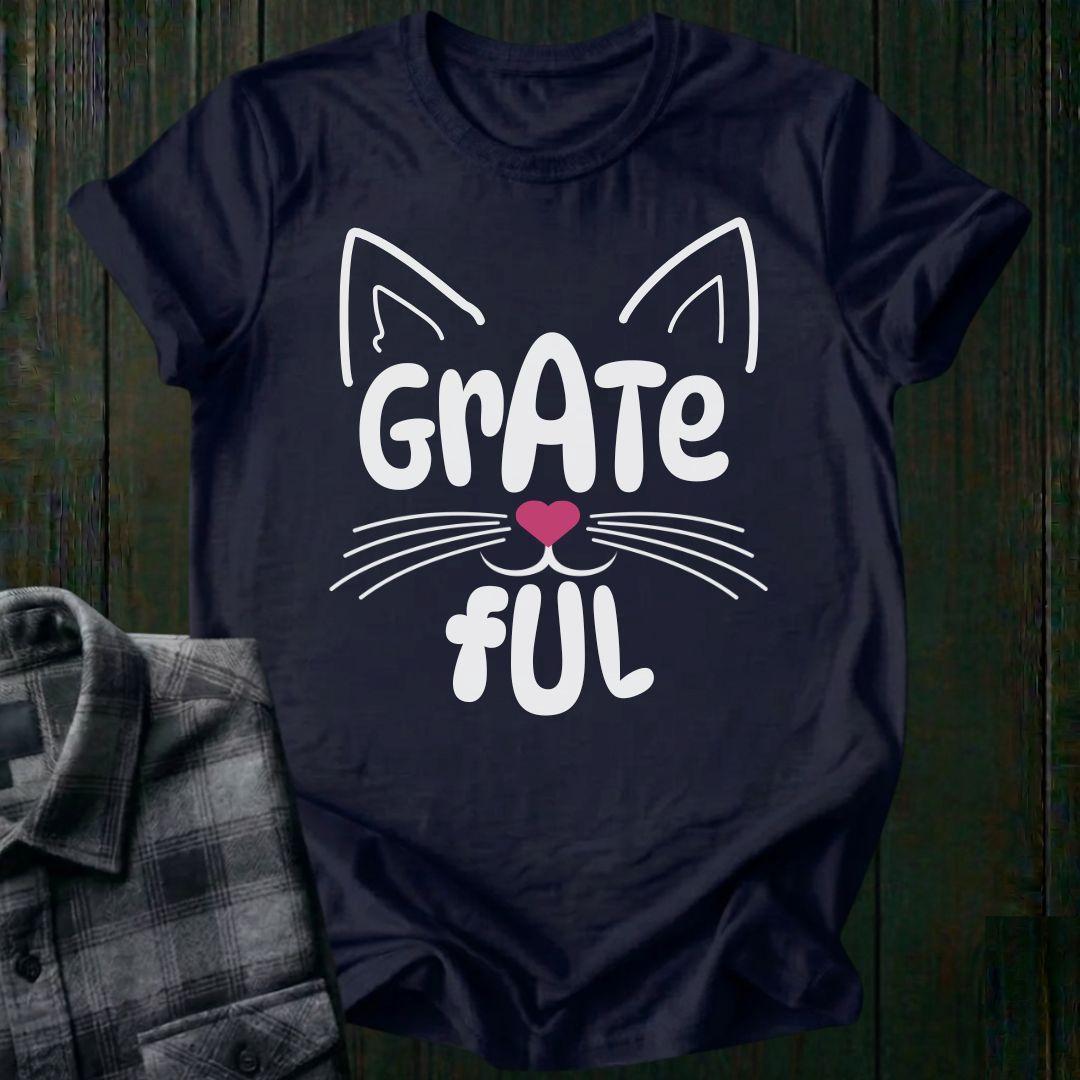 Navy blue t-shirt with white cat graphic and 'Grate Ful' text on a wooden surface.
