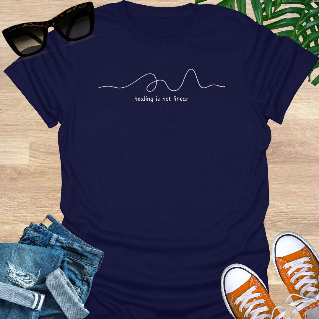 Navy unisex t-shirt with minimalist line art and white text reading healing is not linear
