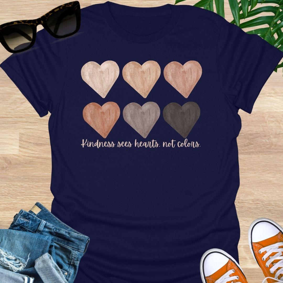 Navy blue t-shirt with six watercolor hearts in diverse skin tones above the script “Kindness sees hearts, not colors” on a unisex tee.