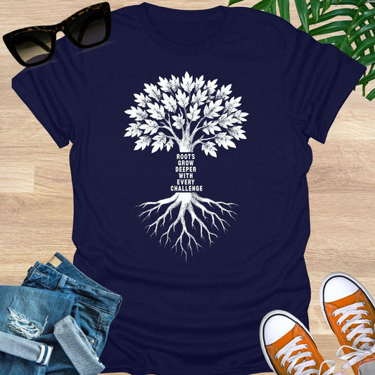 White tree with deep roots and the phrase “Roots grow deeper with every challenge” on a navy unisex tee.