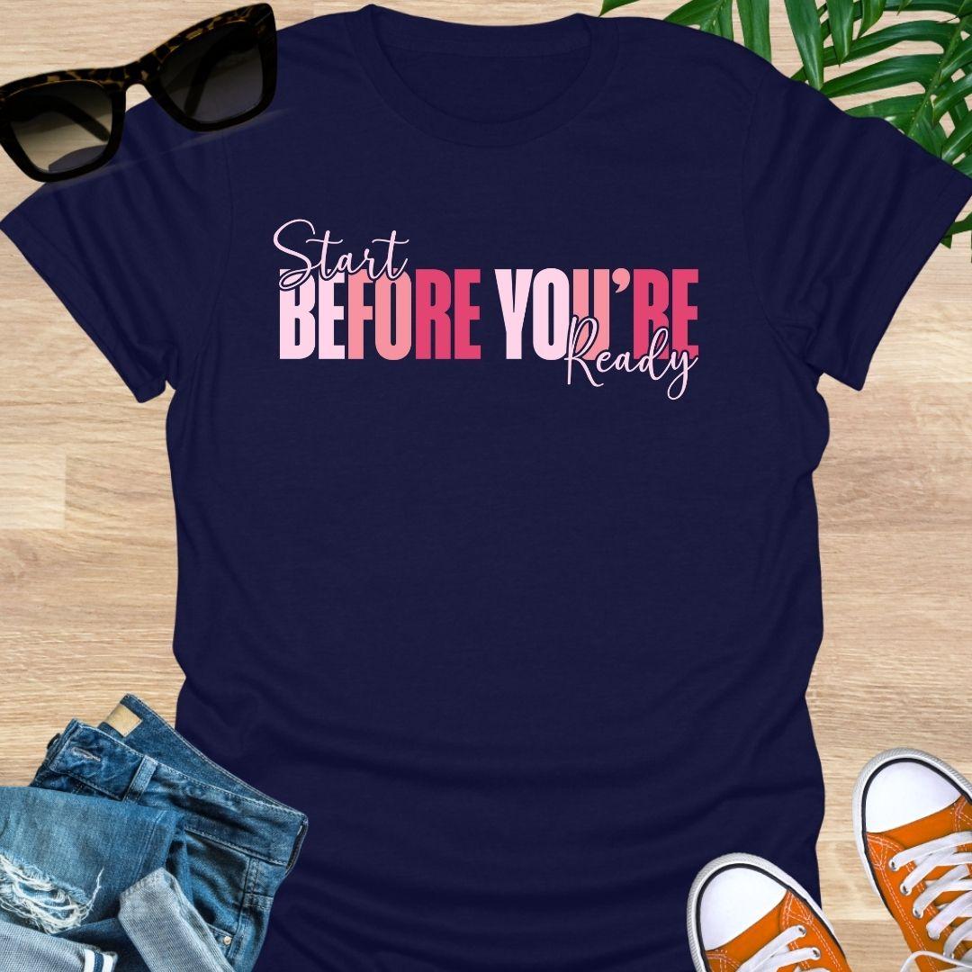 “Start Before You’re Ready” in pink gradient block letters with script overlay on a navy unisex tee.