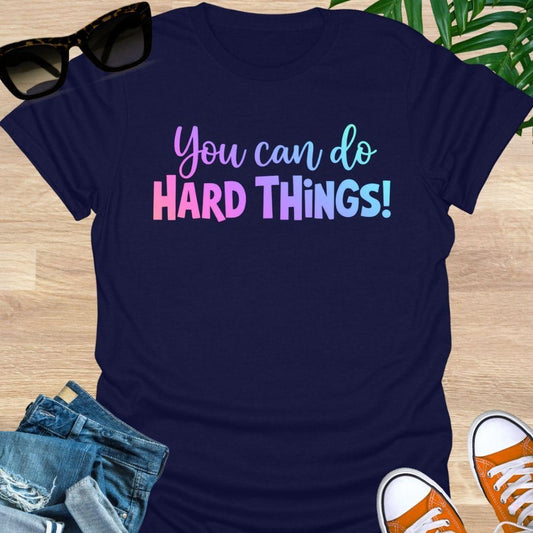 “You Can Do Hard Things” in sunrise gradient lettering on a navy unisex tee.