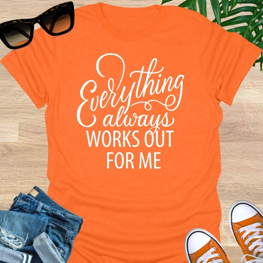 White script text reads “Everything always works out for me” on an orange unisex affirmation tee.