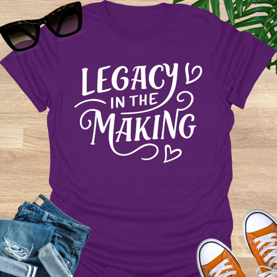 White script “Legacy in the Making” with heart flourishes on a purple motivational graphic tee.