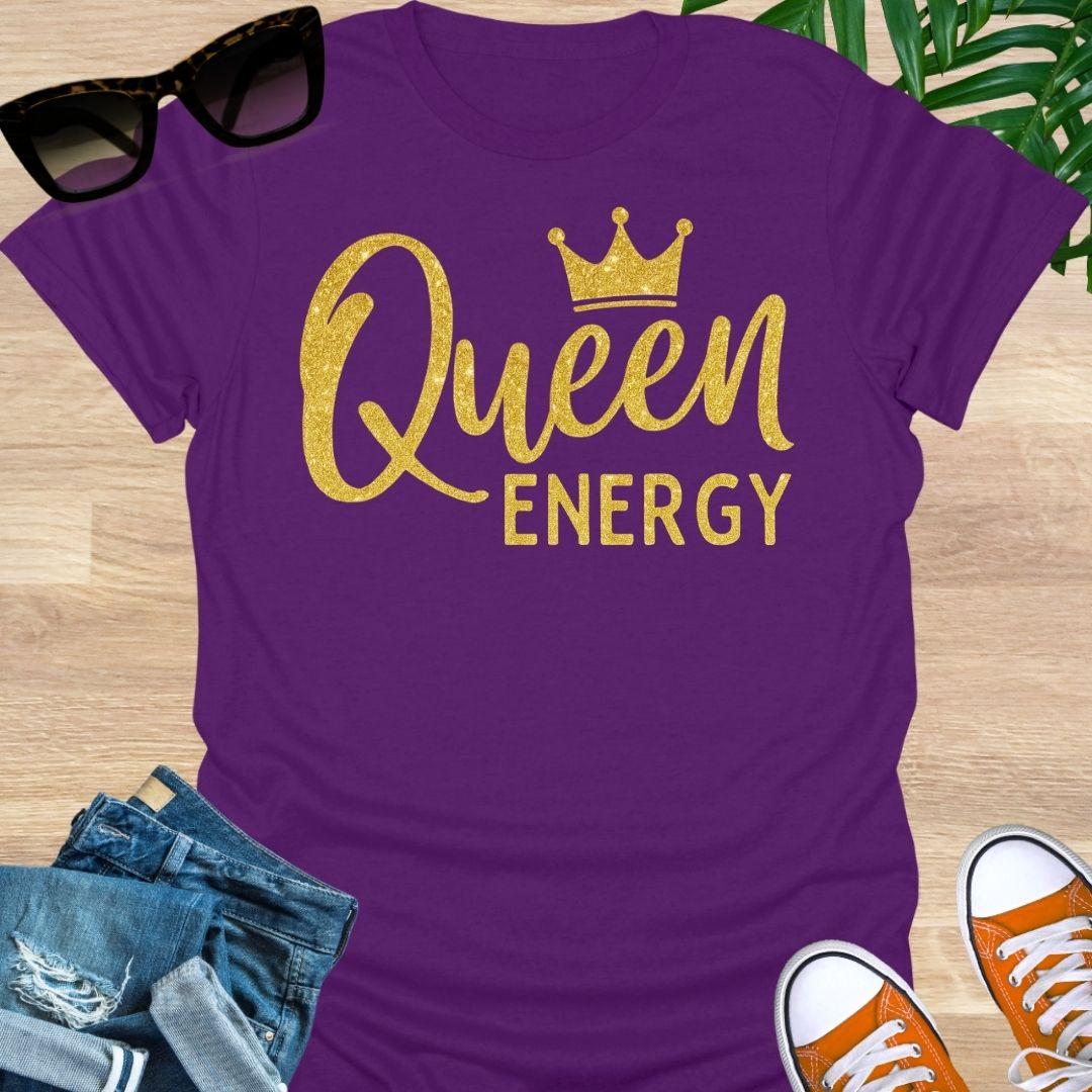 Gold glitter script “Queen Energy” with a crown on a purple empowerment graphic tee.