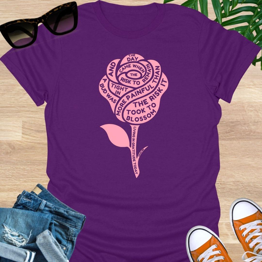 Pink rose with Anaïs Nin “Risk to Blossom” quote on empowerment and growth on purple unisex teeb