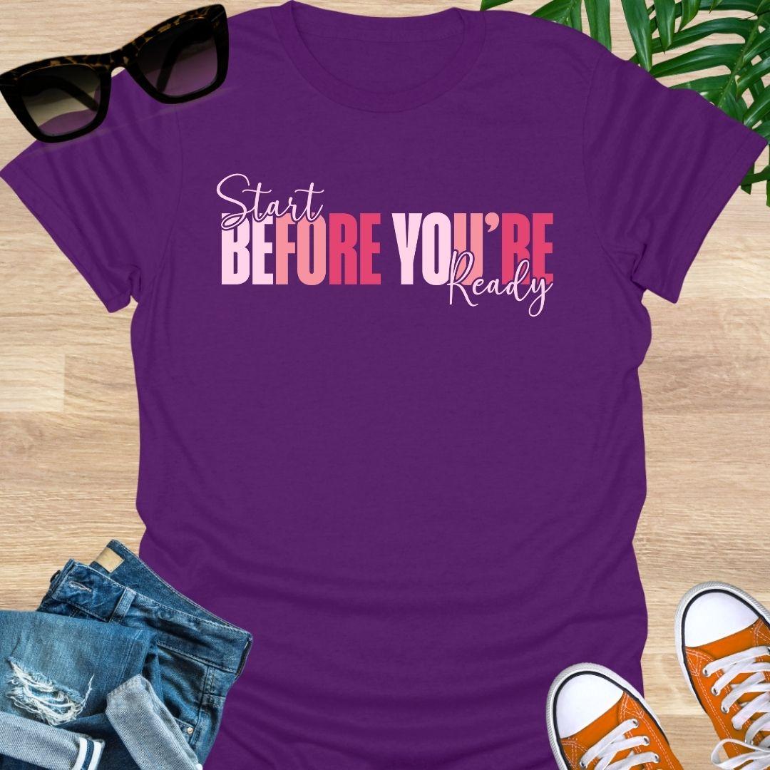 “Start Before You’re Ready” in pink gradient block letters with script overlay on a purple unisex tee.