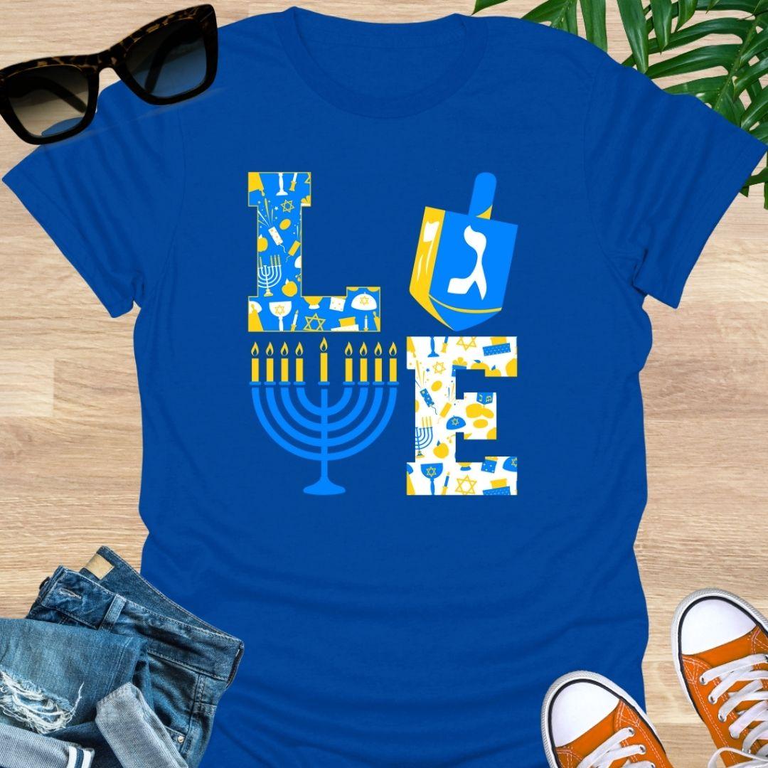 LOVE Hanukkah design with dreidel “O”, menorah “V”, and blue-gold holiday icons on a blue unisex tee.