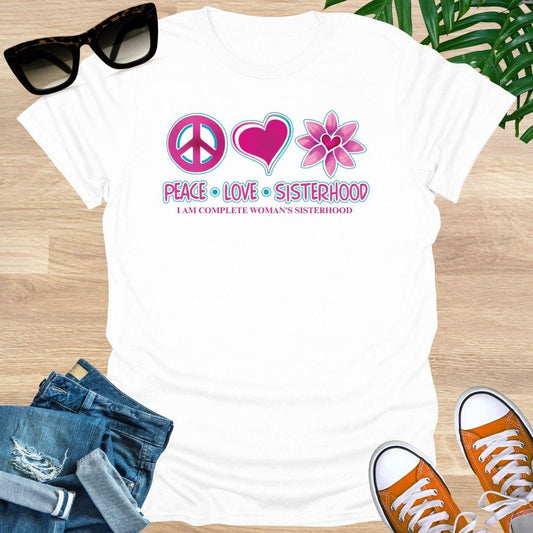 White t-shirt with 'Peace Love Sisterhood' design on a wooden surface with sunglasses, jeans, and sneakers.